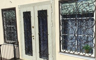двустворчатая дверь в загородный дом с двумя коваными ажурными решетками и двумя стеклопакетам
